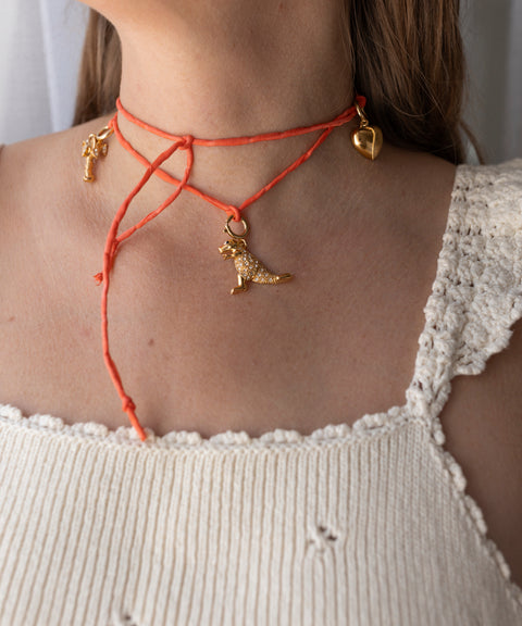 Wearing a cream crochet top and an orange string necklace adorned with gold heart, angel, and dog charms, a participant embodies the playful spirit of WALD Berlin’s DIY charm jewelry Workshop in Esslingen.