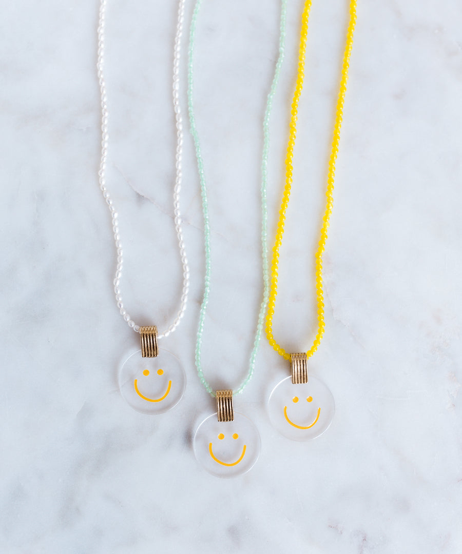 Three jewelry necklaces from WALD Berlin, featuring a smilie dude pearl medaillon design.