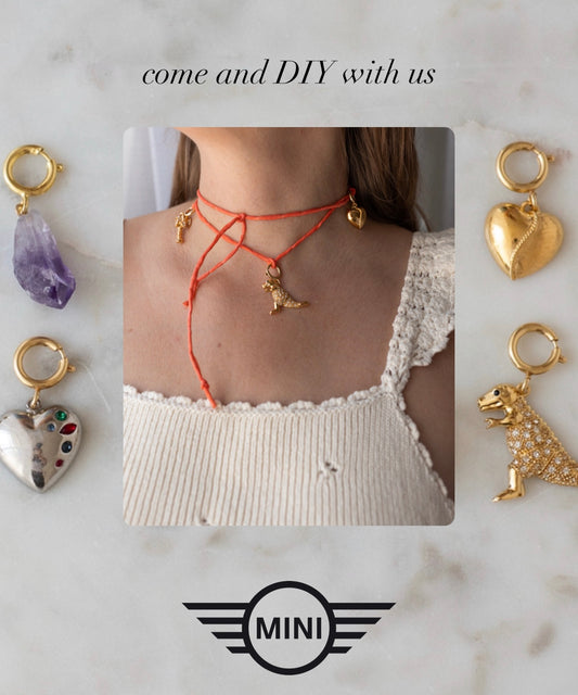 Eine Person trägt eine rote Kette mit goldenen Akzenten. Das Foto wird von vier einzigartigen Anhängern umrahmt: einem Amethyst, einem mit Edelsteinen besetzten Herz, einem goldenen Herz und einem Dinosaurier. Der Text lautet: „Komm und bastle mit uns.“ Nimm am DIY-Schmuck-Workshop x MINI im KaDeWe Berlin von WALD Berlin teil und gestalte dein eigenes, einzigartiges Schmuckstück!.