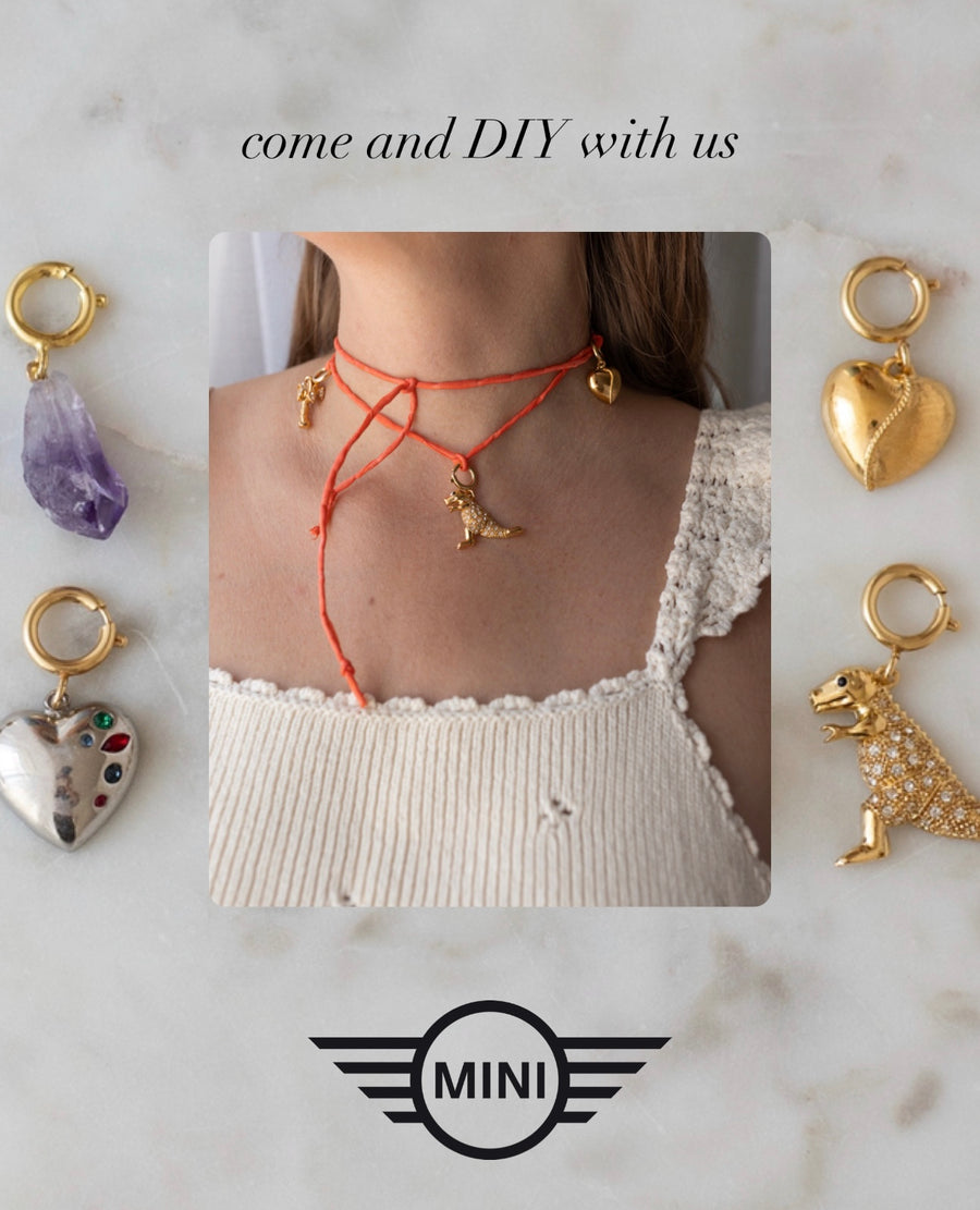 A person wears a red string necklace adorned with gold accents. Surrounding the photo are four unique charms: an amethyst, a jeweled heart, a gold heart, and a dinosaur. Text reads: “come and DIY with us.” Join the DIY Schmuck-Workshop x MINI im KaDeWe Berlin from WALD Berlin and design your own unique jewelry creation!.