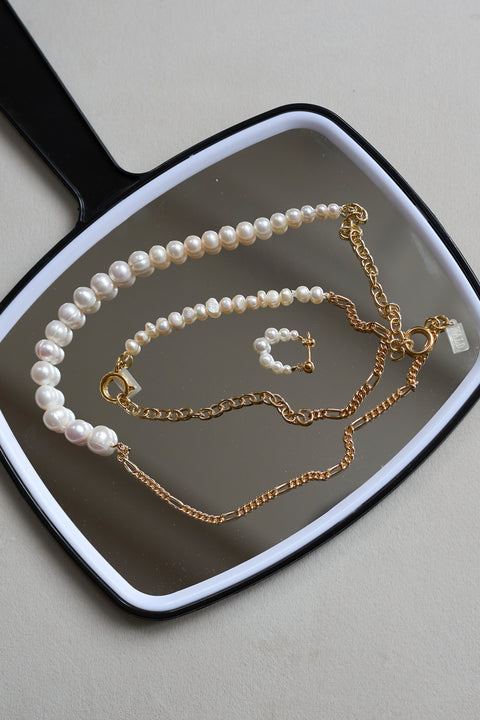 The WALD Berlin Pas De Deux Bracelet / Anklet is elegantly displayed on a black hand mirror, highlighting the brand’s exquisite handmade jewelry design.