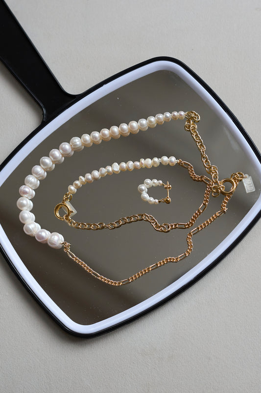 The WALD Berlin Pas De Deux Bracelet / Anklet is elegantly displayed on a black hand mirror, highlighting the brand’s exquisite handmade jewelry design.