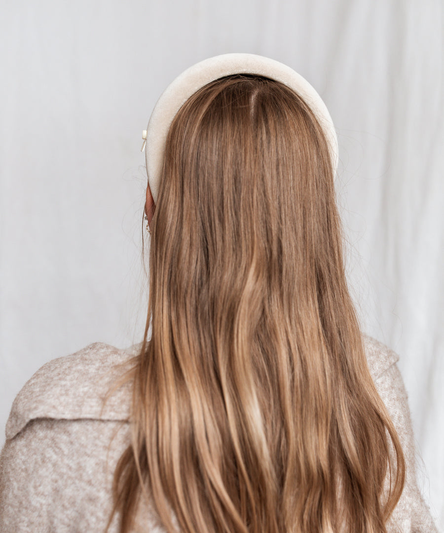 A person with long brown hair, wearing the WALD Berlin Classic White Velvet Headband and a beige textured top, is photographed from behind against a plain white background.