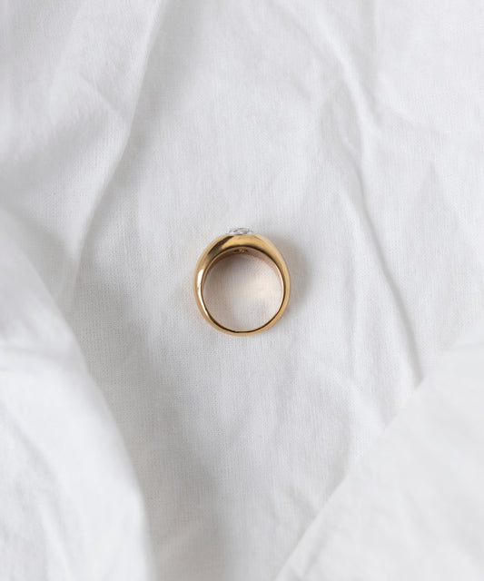 The WALD Berlin Pop Swarovski Ring, crafted from 18k gold-plated brass with a small Swarovski stone, rests elegantly on white crumpled fabric. Made in Germany.