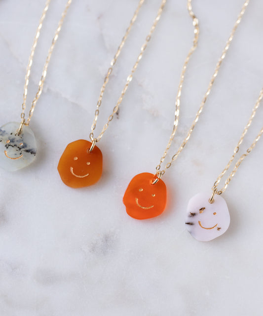 Four WALD Berlin Smilie Dude Gemstone Pendants without chains, featuring vibrant smiley faces, displayed on white marble. Exquisitely crafted in Germany.