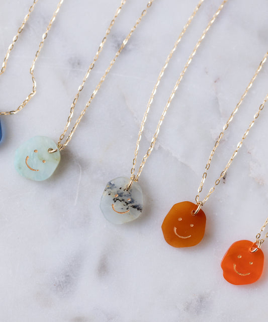 Five Smilie Dude Gemstone Pendants Without Chain by WALD Berlin in various colors with real gemstone accents, shown on a white marble surface.