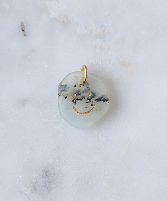 The WALD Berlin Smilie Dude Gemstone Pendant Without Chain features a round, translucent stone with black and gold flecks and a gold smiley face engraving—a distinctive real gemstone accessory crafted in Germany.