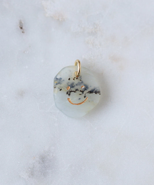 The WALD Berlin Smilie Dude Gemstone Pendant Without Chain features a round, translucent stone with black and gold flecks and a gold smiley face engraving—a distinctive real gemstone accessory crafted in Germany.