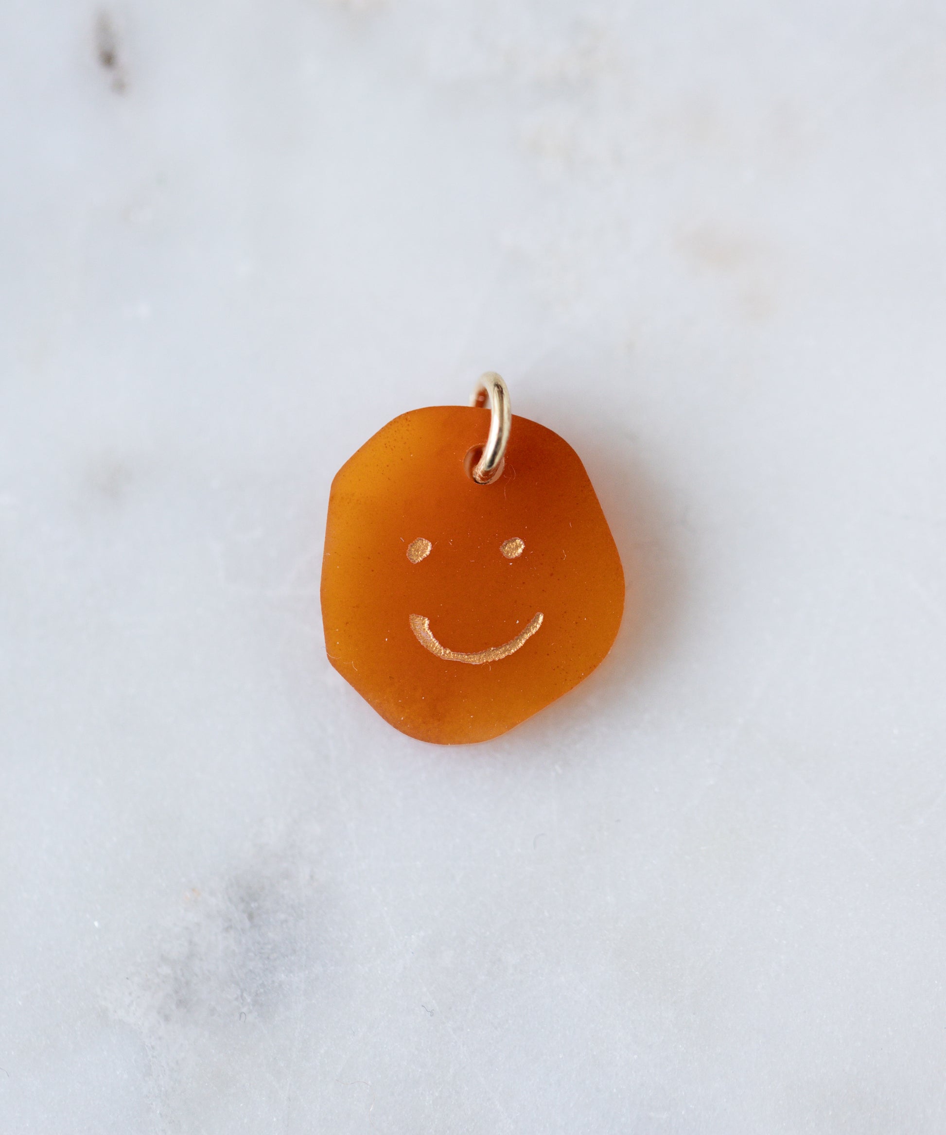 The WALD Berlin Smilie Dude Gemstone Pendant Without Chain is a small, uniquely shaped amber pendant with an engraved smiley face and metal loop—ideal for adding charm to any real gemstone jewelry collection.