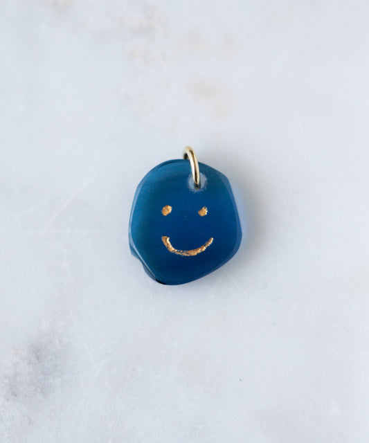 The WALD Berlin Smilie Dude Gemstone Pendant Without Chain features a small blue charm with a gold smiling face and metal loop, made in Germany—an elegant accent for any 18k gold necklace.
