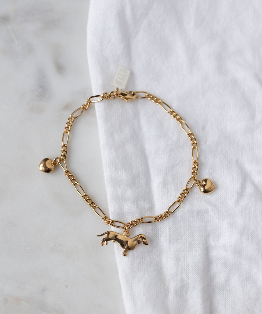 The WALD Berlin SAMPLE SALE Charm Bracelet Z Edition, 18k gold plated with three charms (heart, horse, heart), is displayed on a white fabric surface.