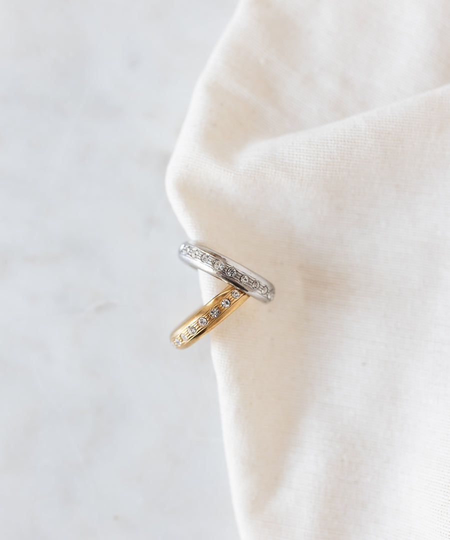 Two stacked Hug Me Earcuff Silver pieces in silver and gold, each set with a row of sparkling Swarovski stones.