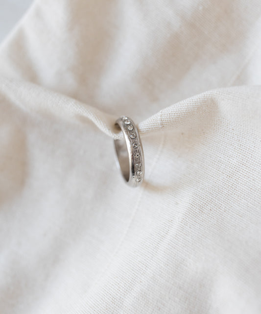 WALD Berlin Hug Me Earcuff Silver inlaid with a row of small, clear Swarovski stones, draped over beige fabric.