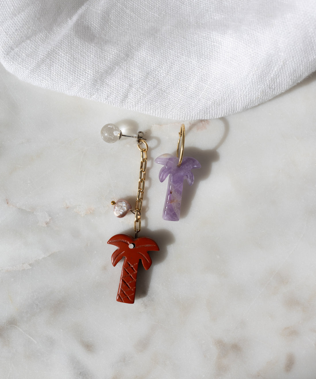 The WALD Berlin Mexicana Mariachi Earrings Double Palm feature red and purple palm designs, one with a gold-plated chain and beads, the other with a gold loop—perfect for adding charm to your jewelry collection.
