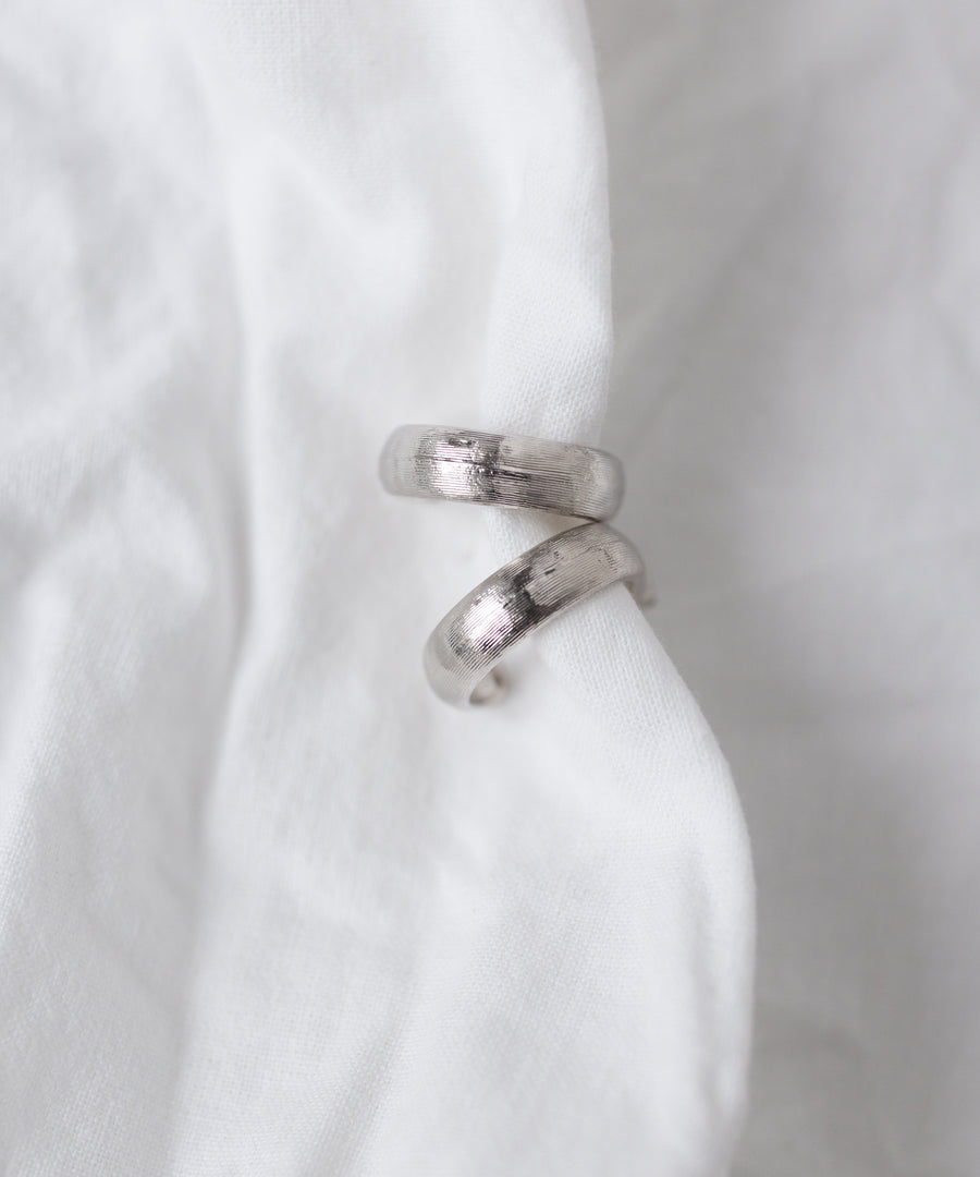 The WALD Berlin SAMPLE SALE Pop Classy Hoop Silver earrings are displayed on a white fabric background.