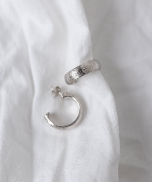 The SAMPLE SALE Pop Classy Hoop Silver earrings by WALD Berlin are displayed on a white fabric background, highlighting their elegant craftsmanship.
