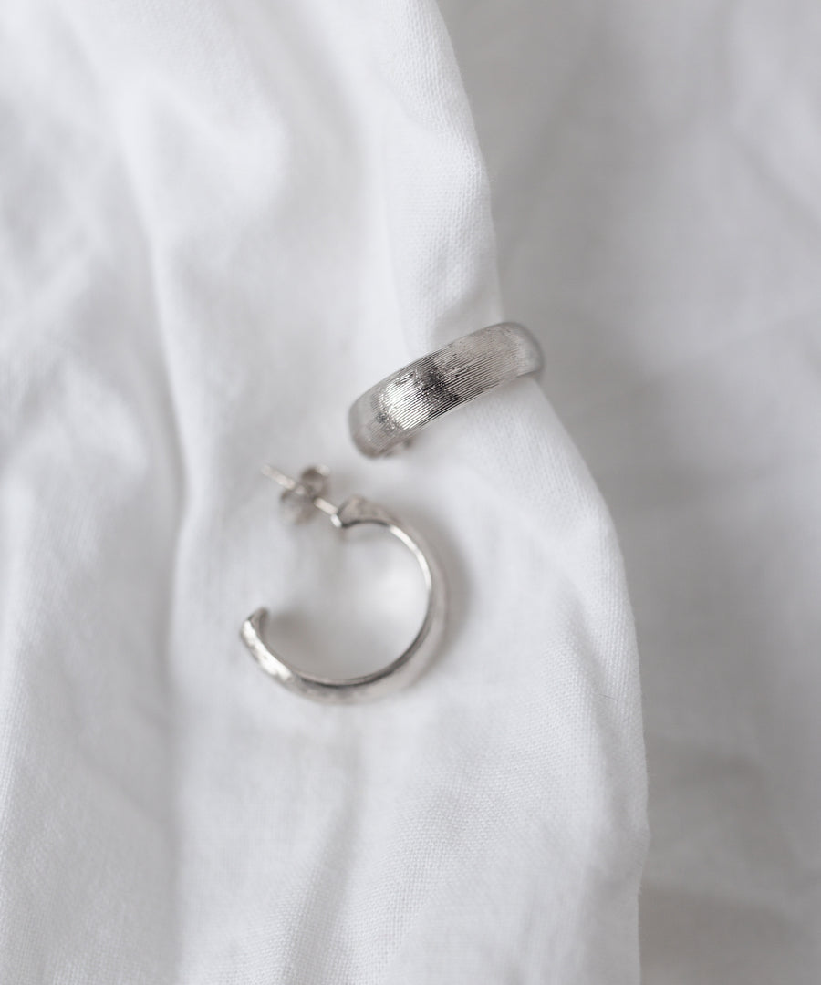 The SAMPLE SALE Pop Classy Hoop Silver earrings by WALD Berlin are displayed on a white fabric background, highlighting their elegant craftsmanship.