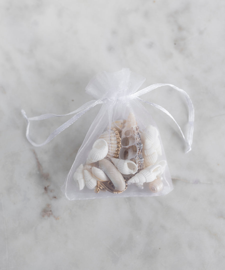 The WALD Berlin Candyman Shell Kit features a small white mesh drawstring bag filled with assorted handpicked seashells, displayed on a light marble surface.