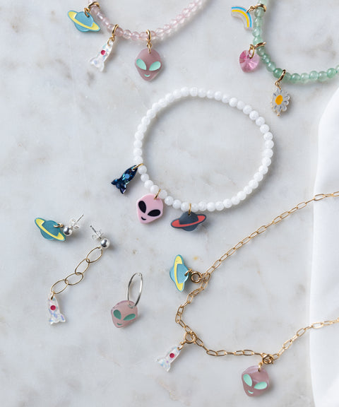 Add some galactic flair to your look with the SAMPLE SALE From Another Mother Galactic Earring Set by WALD Berlin—featuring playful alien, rocket, spaceship, and rainbow charms in 925 sterling silver and gold accents, all beautifully presented.
