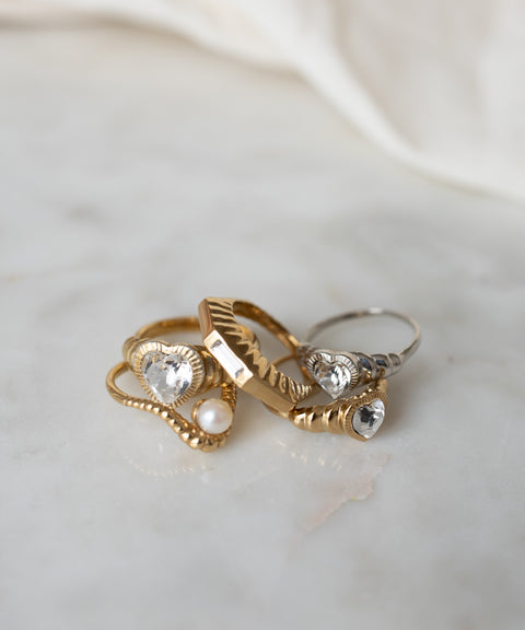 A collection of Be My Lover Mini Silver Rings with Swarovski stones and pearls on a marble surface by WALD Berlin.