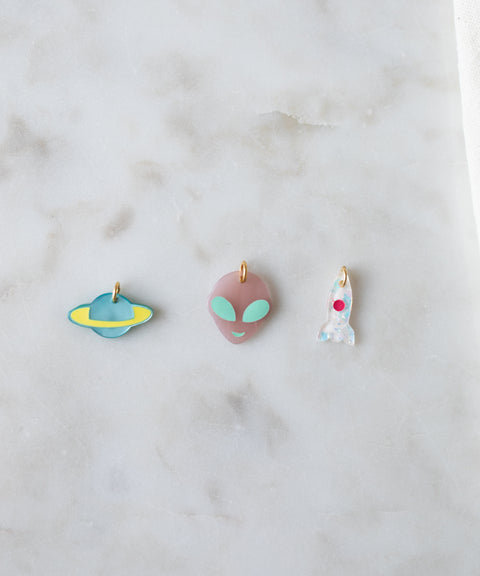 Three Venus Charm keychains with designs of a UFO, an alien face, and a ghost, displayed on a marble surface perfect for DIY jewelry enthusiasts from WALD World.