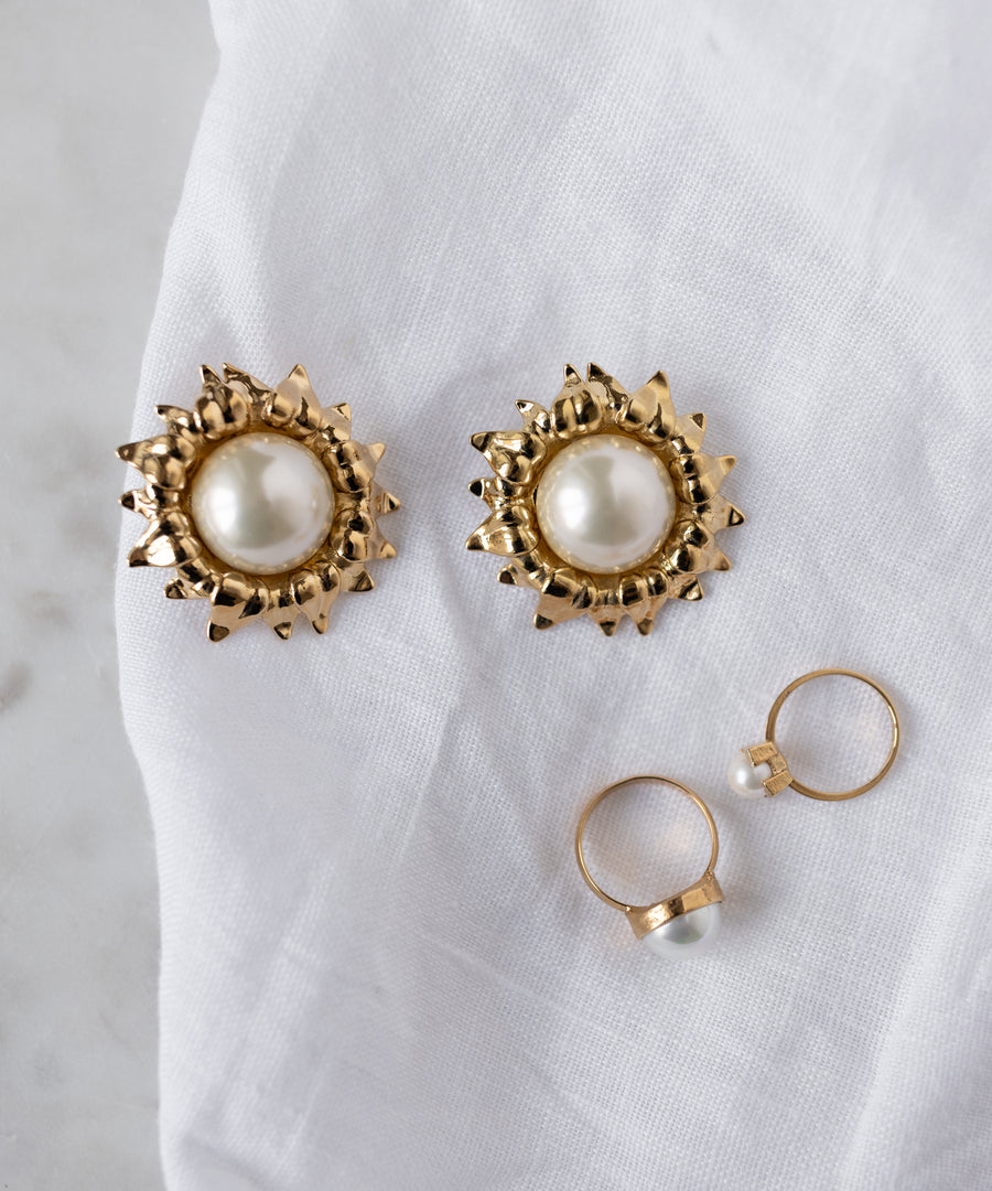 WALD Berlin gold earrings with large round pearl centers and the SAMPLE SALE Pop Pearl Ring, all made in Germany, displayed on a white fabric background.
