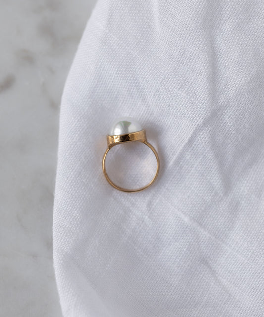 The WALD Berlin SAMPLE SALE Pop Pearl Ring features a single white pearl atop 18k gold plated metal, elegantly displayed on white fabric. Made in Germany.