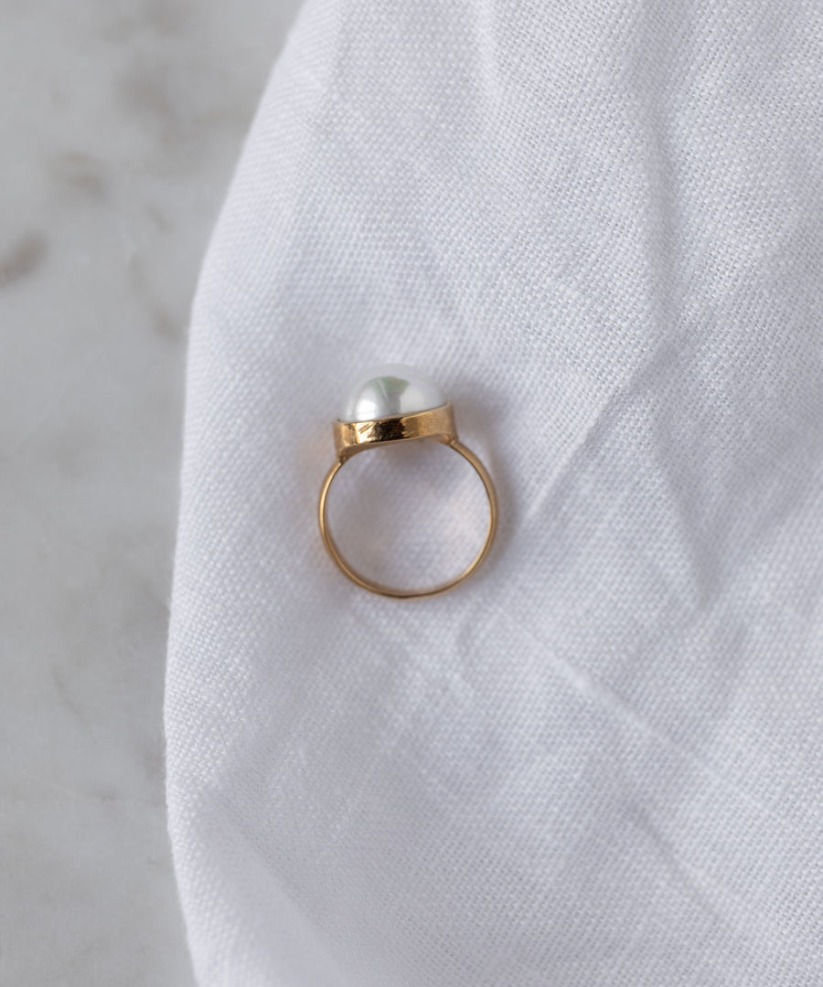 The WALD Berlin SAMPLE SALE Pop Pearl Ring features a single white pearl atop 18k gold plated metal, elegantly displayed on white fabric. Made in Germany.
