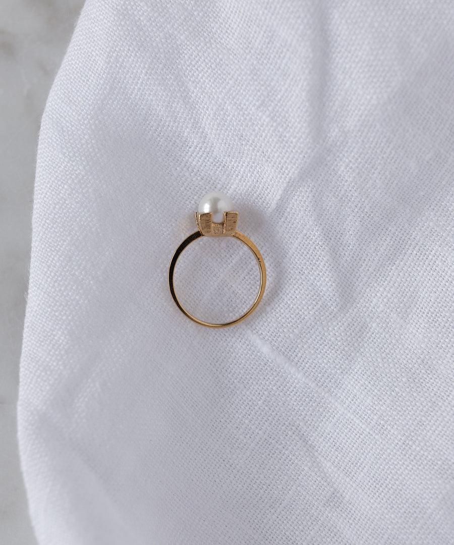 The WALD Berlin SAMPLE SALE Pop Pearl Ring Mini, crafted from gold-plated brass, is displayed on a white cloth background.