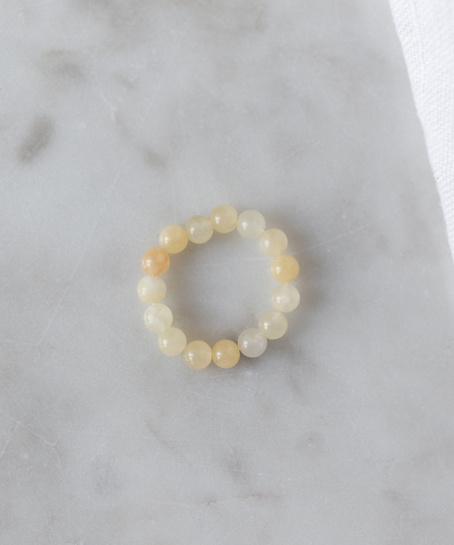 The WALD Berlin Pop Gemstone Ring Set features round, translucent yellow stones and an adjustable fit, displayed on light gray marble—perfect for unique gift ideas.