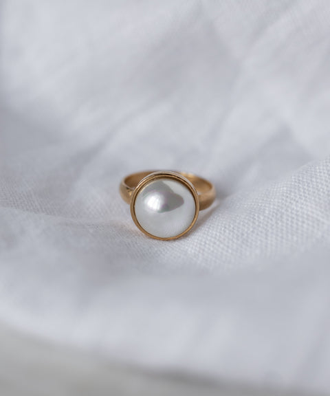 The WALD Berlin SAMPLE SALE Pop Pearl Ring features a large round white pearl set in 18k gold plated metal, beautifully displayed on a white fabric background. Made in Germany.