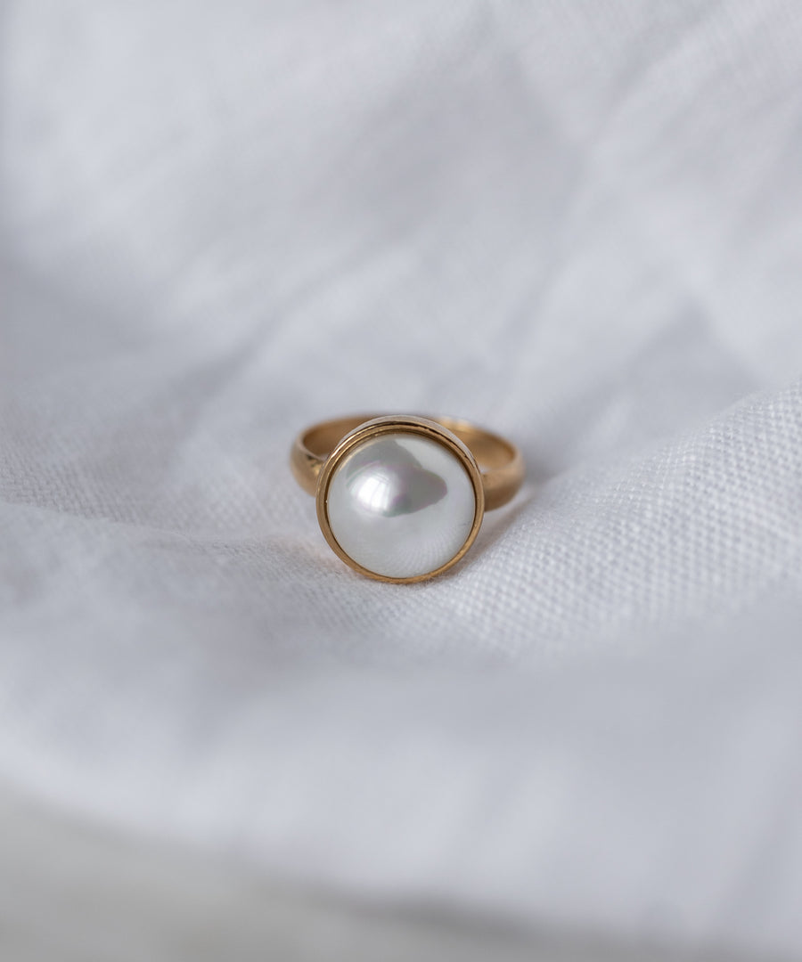 The WALD Berlin SAMPLE SALE Pop Pearl Ring features a large round white pearl set in 18k gold plated metal, beautifully displayed on a white fabric background. Made in Germany.