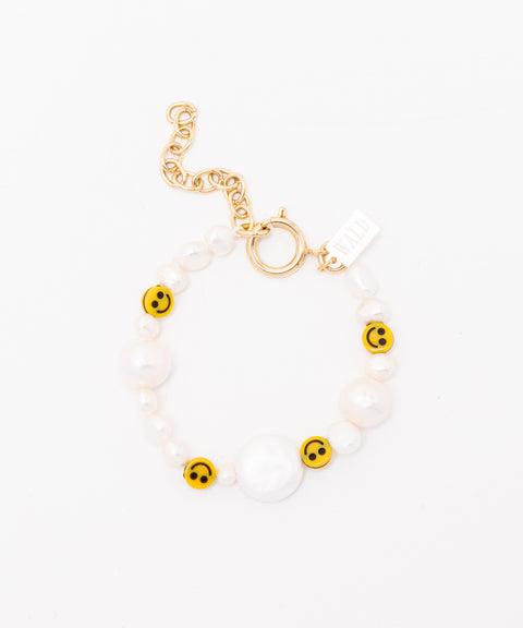 The WALD Berlin "Smilie Dude Pearl Bracelet with Extension" features yellow smiley face beads, sweetwater pearls, and a gold chain and clasp set against a pristine white background.