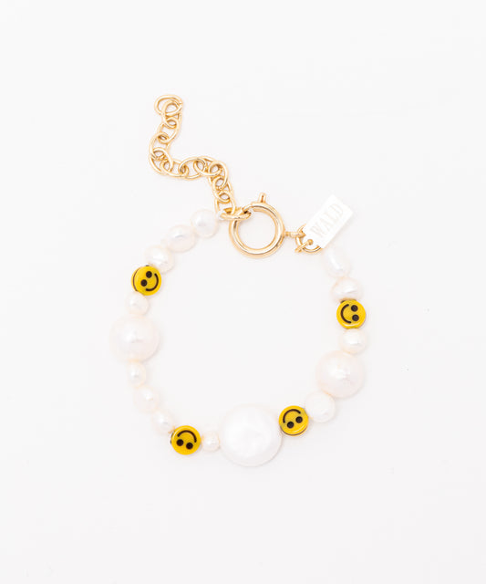 The WALD Berlin "Smilie Dude Pearl Bracelet with Extension" features yellow smiley face beads, sweetwater pearls, and a gold chain and clasp set against a pristine white background.