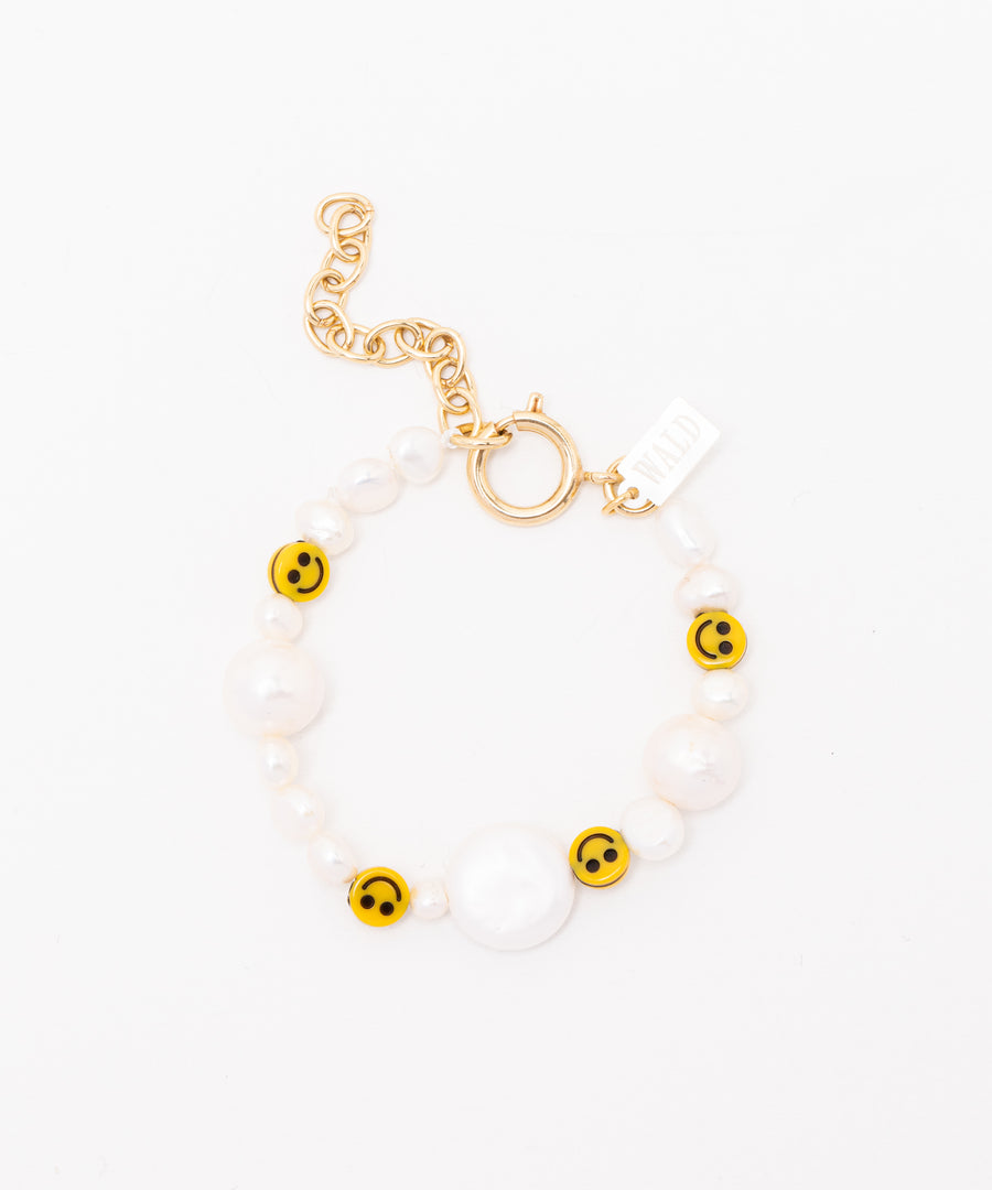The WALD Berlin "Smilie Dude Pearl Bracelet with Extension" features yellow smiley face beads, sweetwater pearls, and a gold chain and clasp set against a pristine white background.