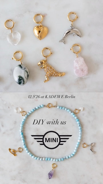 Six gold charms and a blue beaded bracelet are showcased. Text reads “DIY Schmuck-Workshop x MINI im KaDeWe Berlin” by WALD Berlin and “12.9.26.” Join us for this exclusive workshop and discover the joy of DIY jewelry making—Schmuck selber machen—in the heart of Berlin!.
