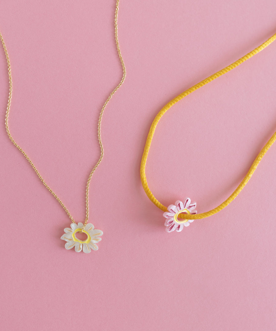 Two DIY jewelry necklaces on a pink background.