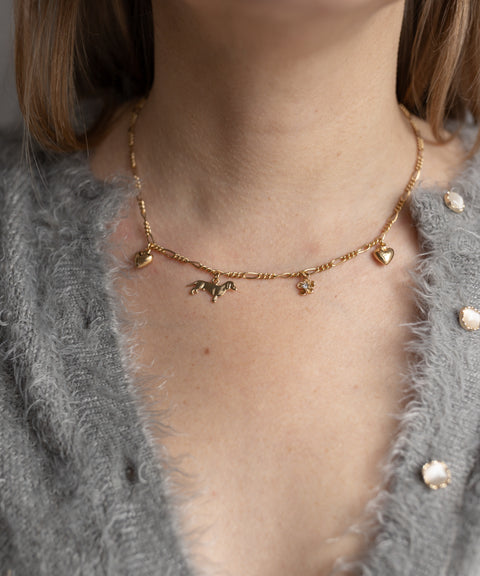 Someone wears the WALD Berlin SAMPLE SALE Charm Necklace Z Edition—an 18k gold-plated necklace with heart and animal charms—over a gray fuzzy buttoned sweater.