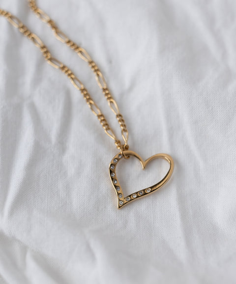 The WALD Berlin SAMPLE SALE Valentine’s Day special sketch heart necklace features a heart pendant with sparkling Swarovski stones on an 18k goldplated chain, elegantly displayed on white fabric.
