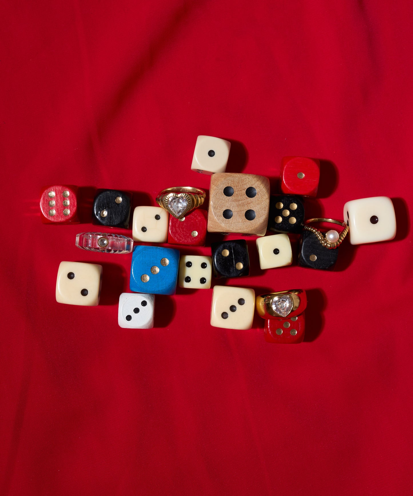 The WALD Berlin Shining Star Crystal Ring is displayed alongside assorted dice on a red fabric background.