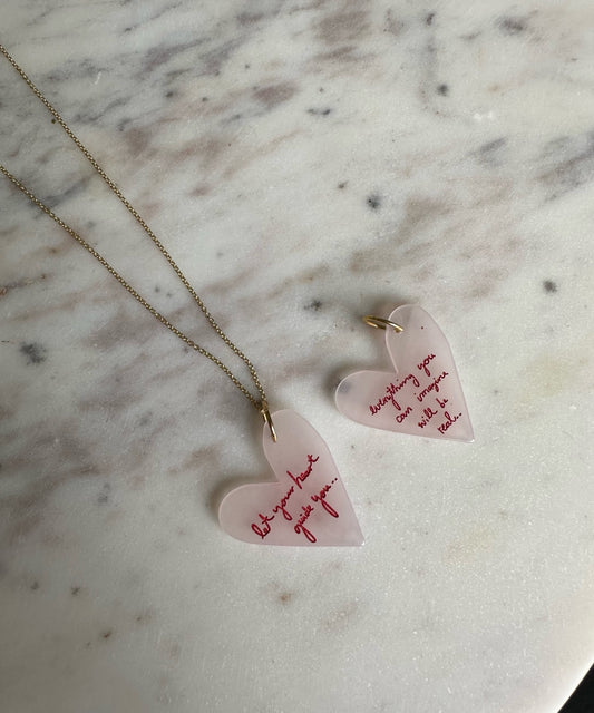 A pair of WALD Berlin Everything You Can Imagine Will Be Real necklaces and earrings on a marble table.
