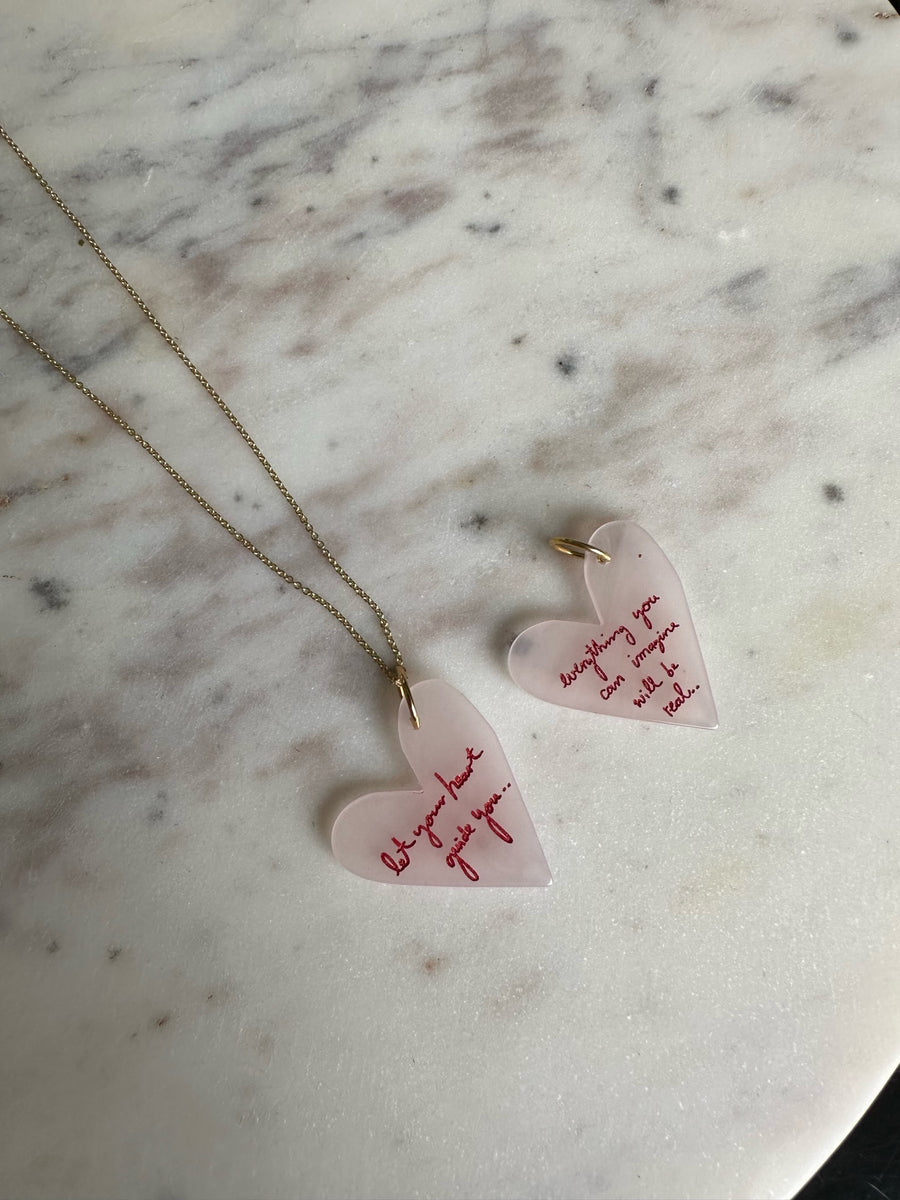 A pair of WALD Berlin Everything You Can Imagine Will Be Real necklaces and earrings on a marble table.
