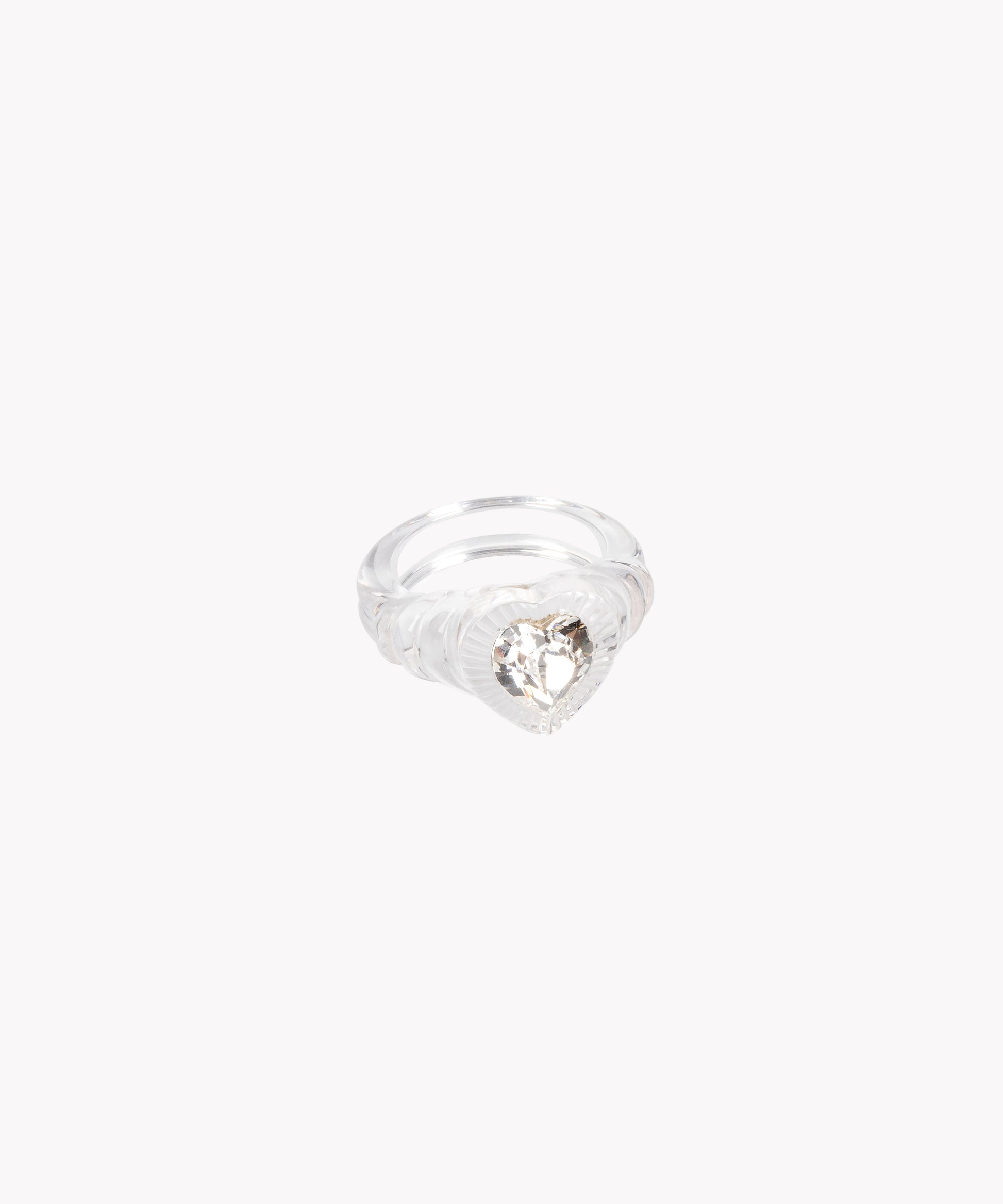 The Be My Lover Transparent Ring SAMPLE from WALD Berlin showcases a heart-shaped Swarovski stone in a clear band, elegantly displayed on a white background.