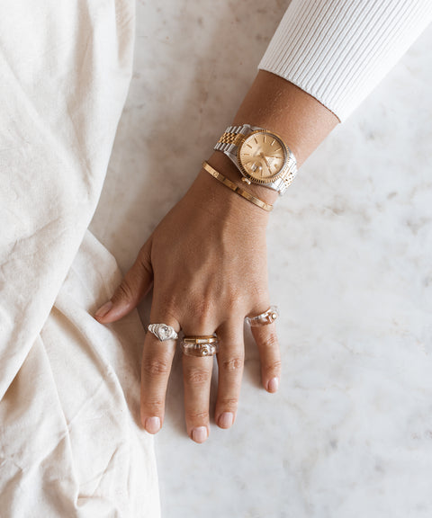 A woman's wrist adorned with a WALD Berlin jewelry, including a Shining Star Crystal Ring and watch.