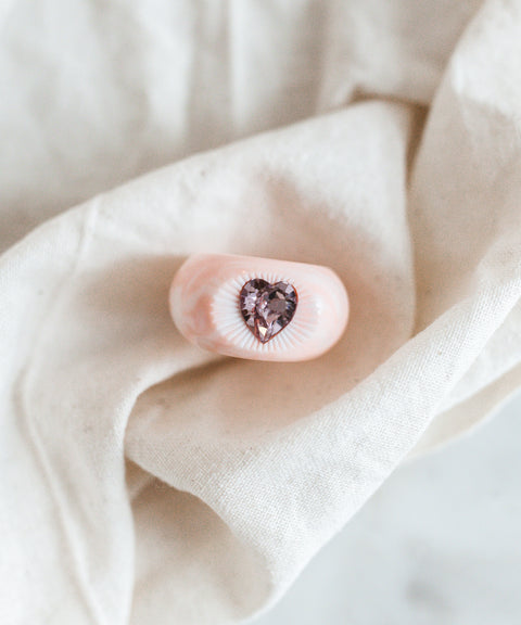 A love-inspired pink heart-shaped WALD x Zeena Rose Heart Ring on a white cloth. (Brand: WALD Berlin)