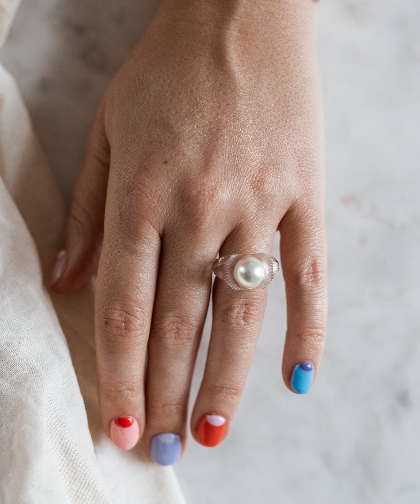 A woman's hand wearing a WALD Berlin Happy No No No Ring, showcasing the vibrant jewelry of Germany.