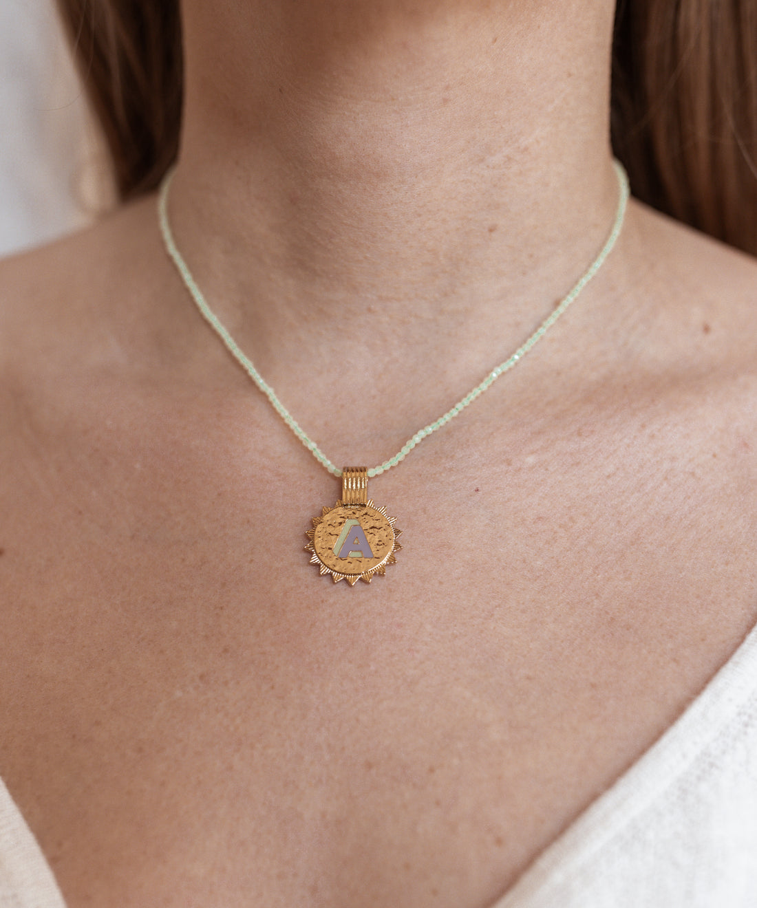A woman wearing a WALD Berlin Say My Name Mint Necklace with a gold triangle pendant.