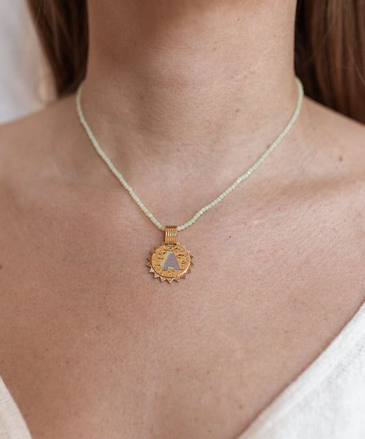 A woman wearing a WALD Berlin Say My Name Mint Necklace with a gold triangle pendant.