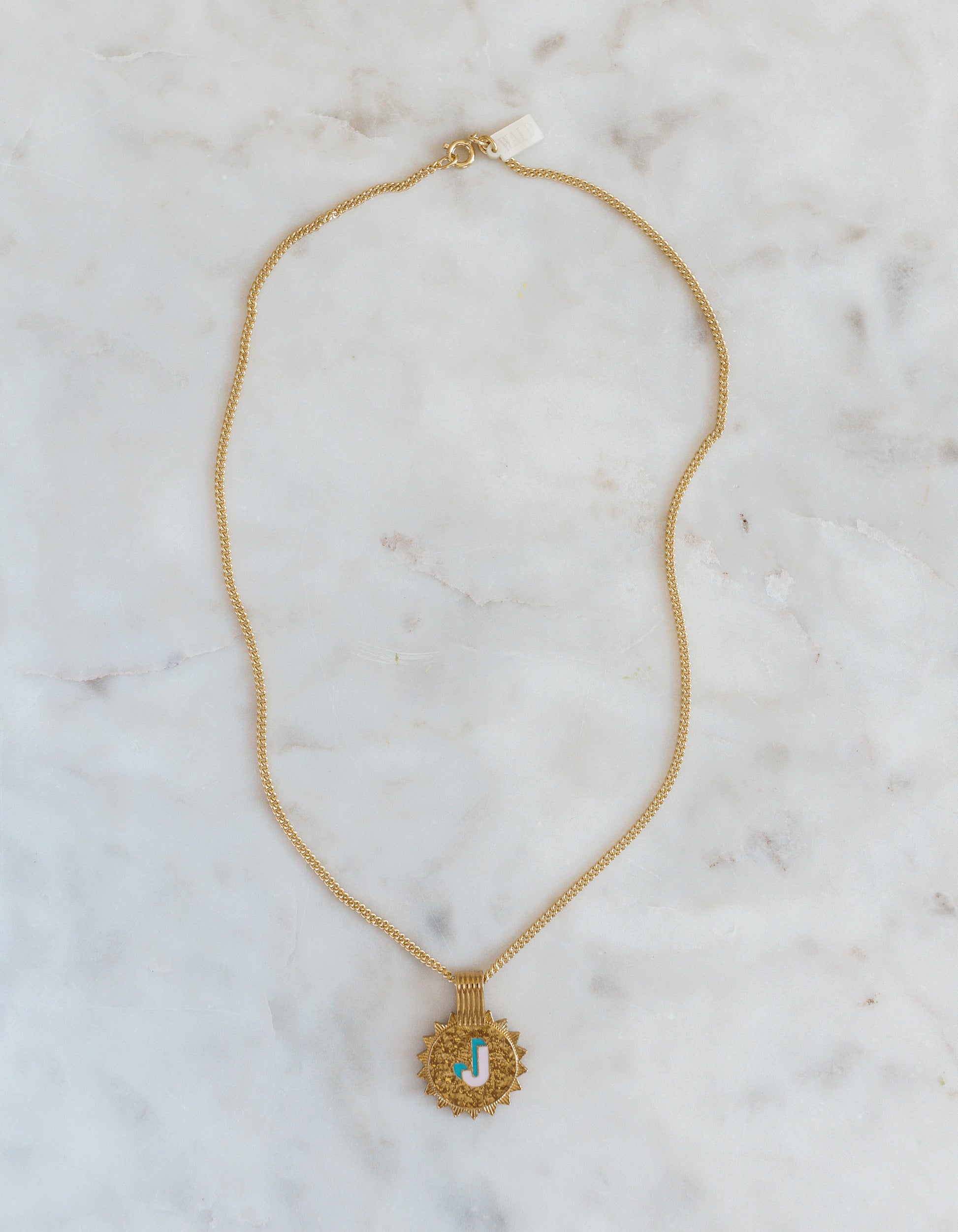 The WALD Berlin Sample saleSay My Name Gold Necklace features a gold-plated chain with a round turquoise and gold letter "J" pendant, displayed on light marble—a stylish initial necklace for any occasion.
