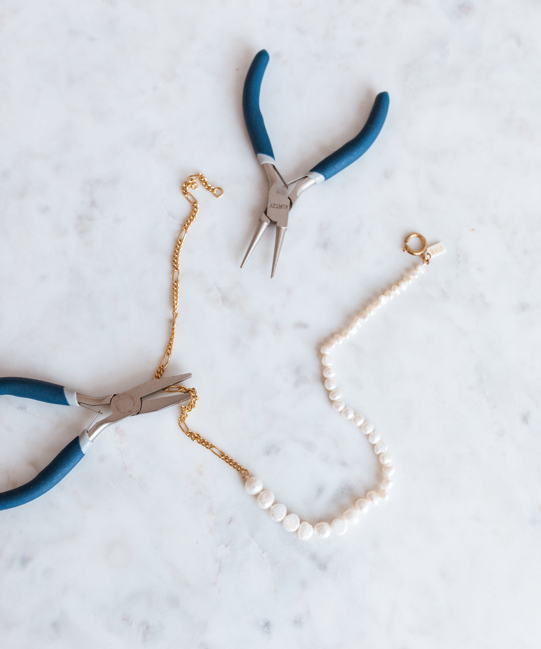 A pair of WALD Berlin pliers and a WALD Berlin pearl necklace on a table in Germany.